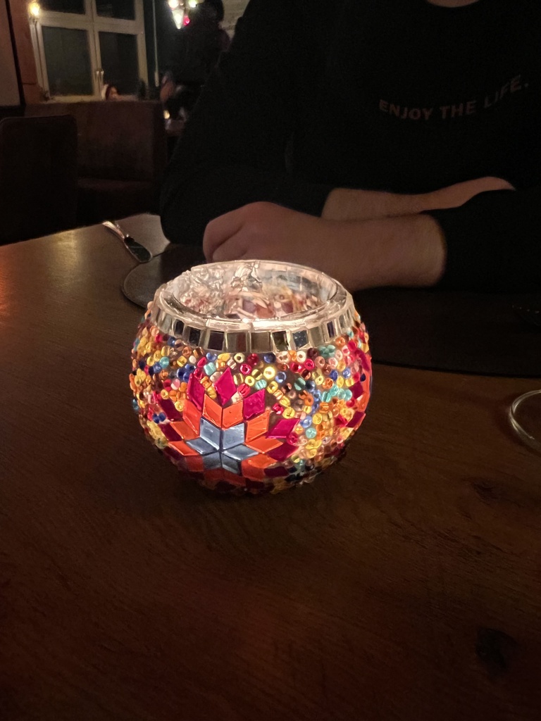 A candleholder glowing on a wooden table capturing the warm, intimate atmosphere of the restaurant and visually representing the connection and the shared experience described in this story.